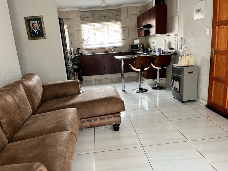 Open-plan living area featuring tiled flooring and a functional kitchen with built-in cabinetry and a breakfast counter.