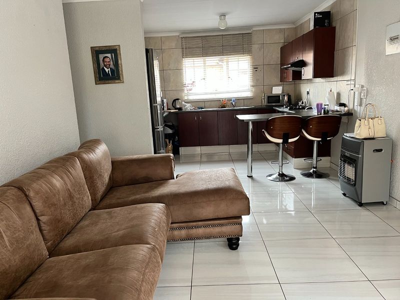 Open-plan living area featuring a functional kitchen with built-in cabinetry, breakfast counter, and tiled flooring throughout.
