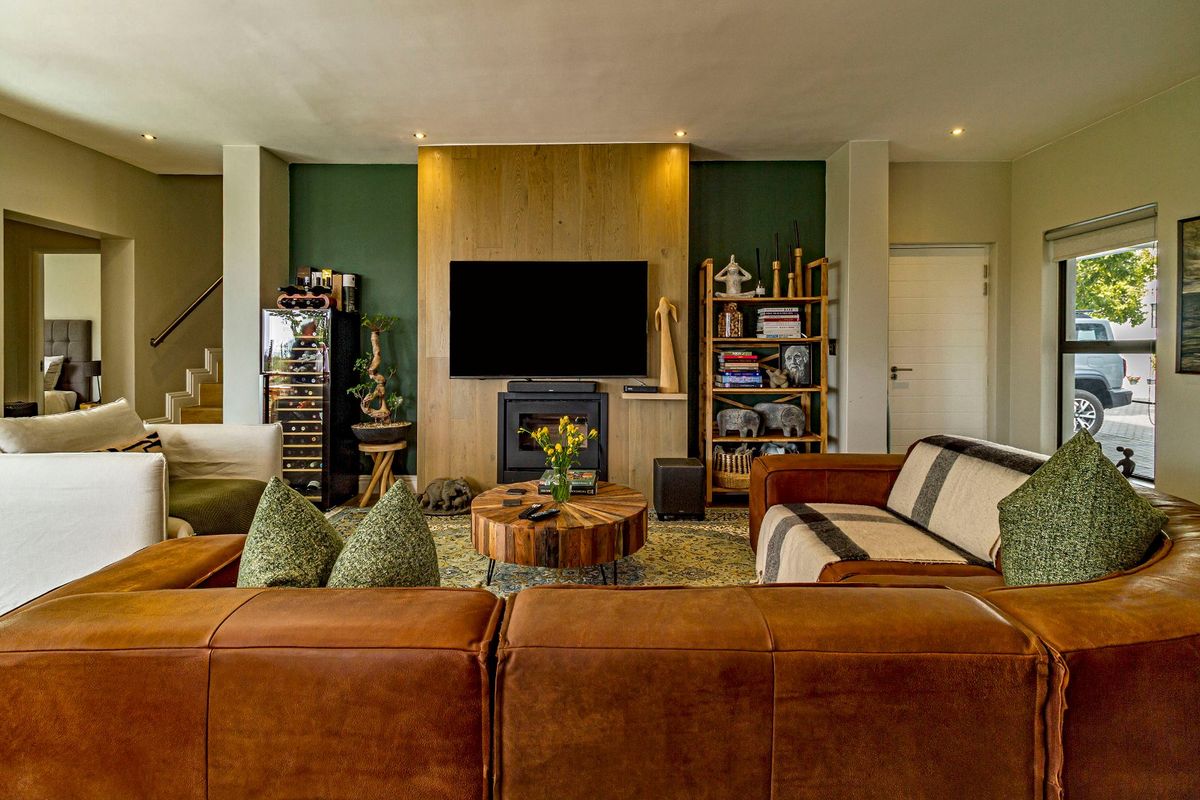 A well-appointed living room featuring a central timber-clad fireplace wall, recessed lighting, and a warm, inviting atmosphere.