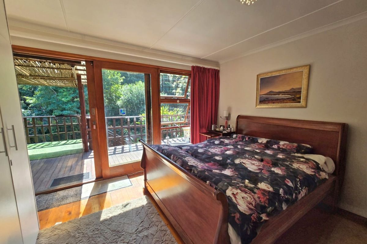 A well-maintained bedroom featuring timber flooring, built-in wardrobes, and large sliding doors that open onto a private wooden deck.