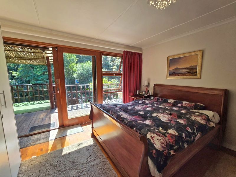 A well-maintained bedroom featuring timber flooring, built-in wardrobes, and large sliding doors that open onto a private wooden deck.