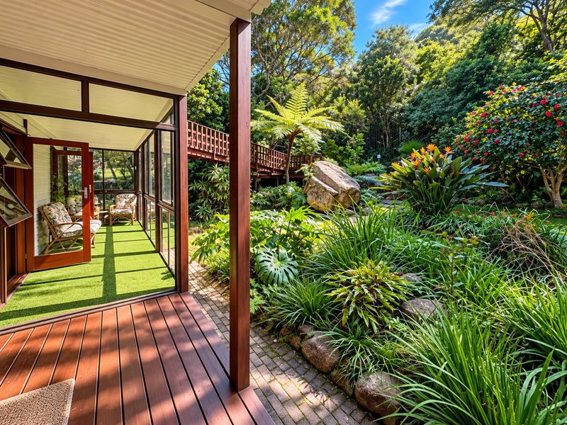 A covered timber deck leading to an enclosed sunroom, overlooking a lush, landscaped garden with an elevated walkway and mature greenery.