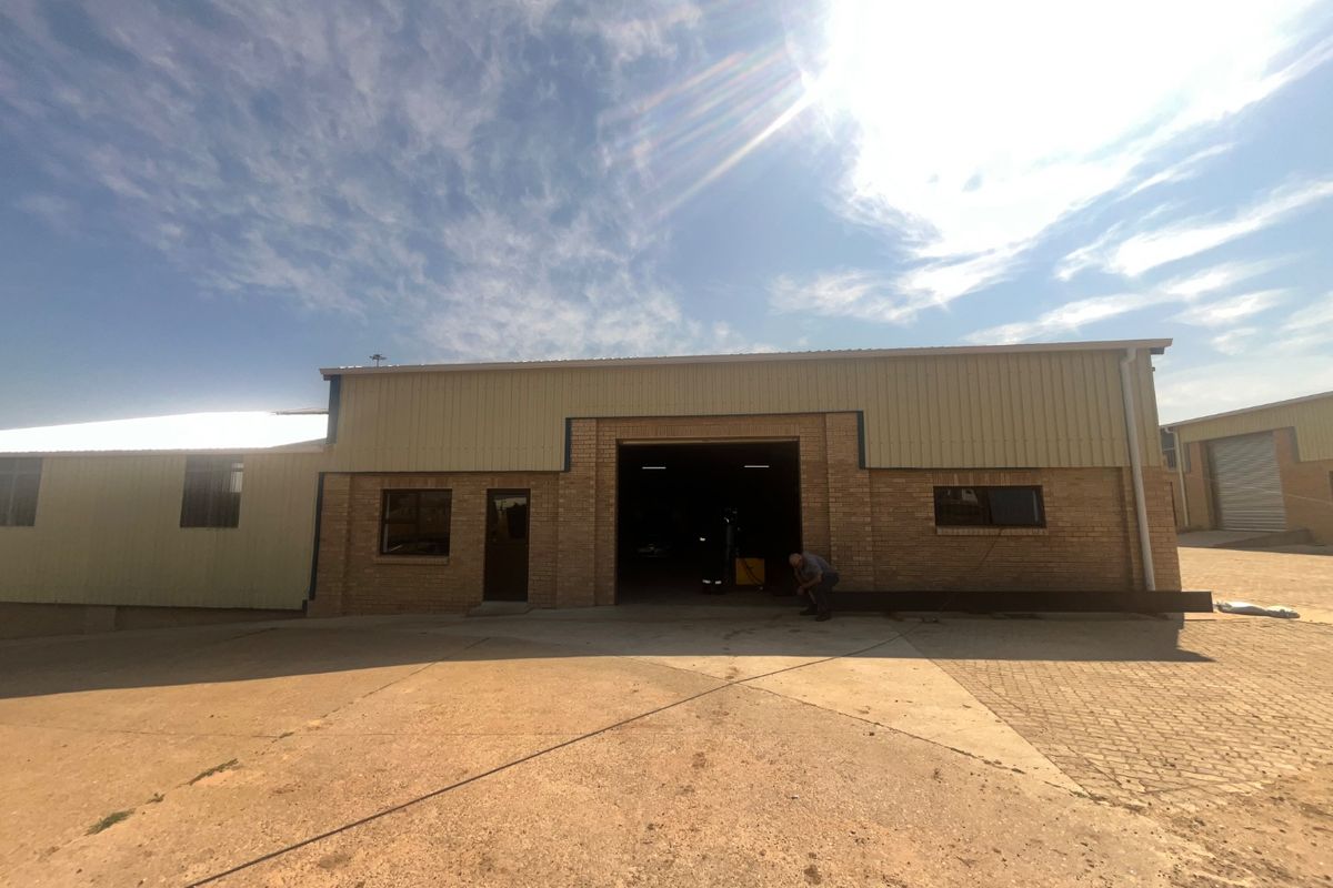 Front elevation of an industrial warehouse featuring a face brick facade, corrugated metal upper cladding, and a large central roller door entrance.