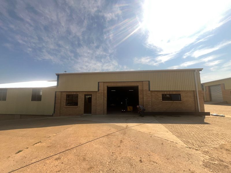 Front elevation of an industrial warehouse featuring a face brick facade, corrugated metal upper cladding, and a large central roller door entrance.