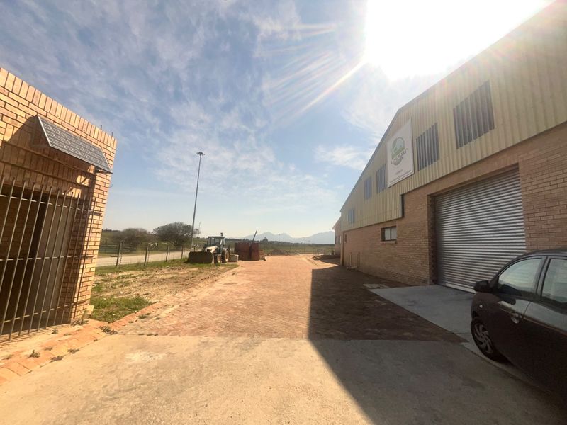 Industrial property exterior featuring a large roller shutter door, face brick construction, and paved yard area with secure perimeter fencing.