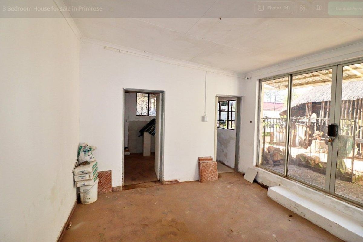 An empty living area featuring concrete flooring, coved ceilings, and a large sliding glass door providing access to the exterior.