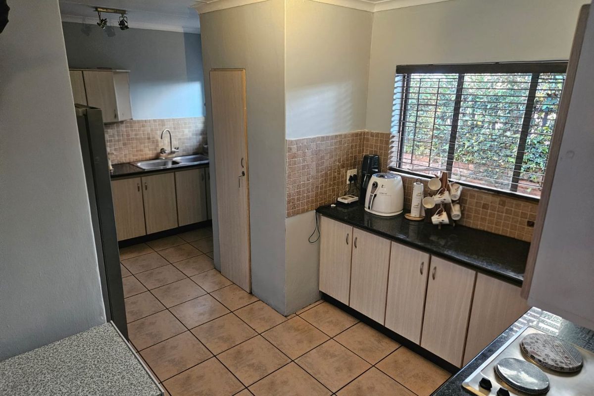 Functional kitchen featuring laminate cabinetry, granite countertops, double basin sink, and ceramic tile flooring with a window overlooking the exterior.