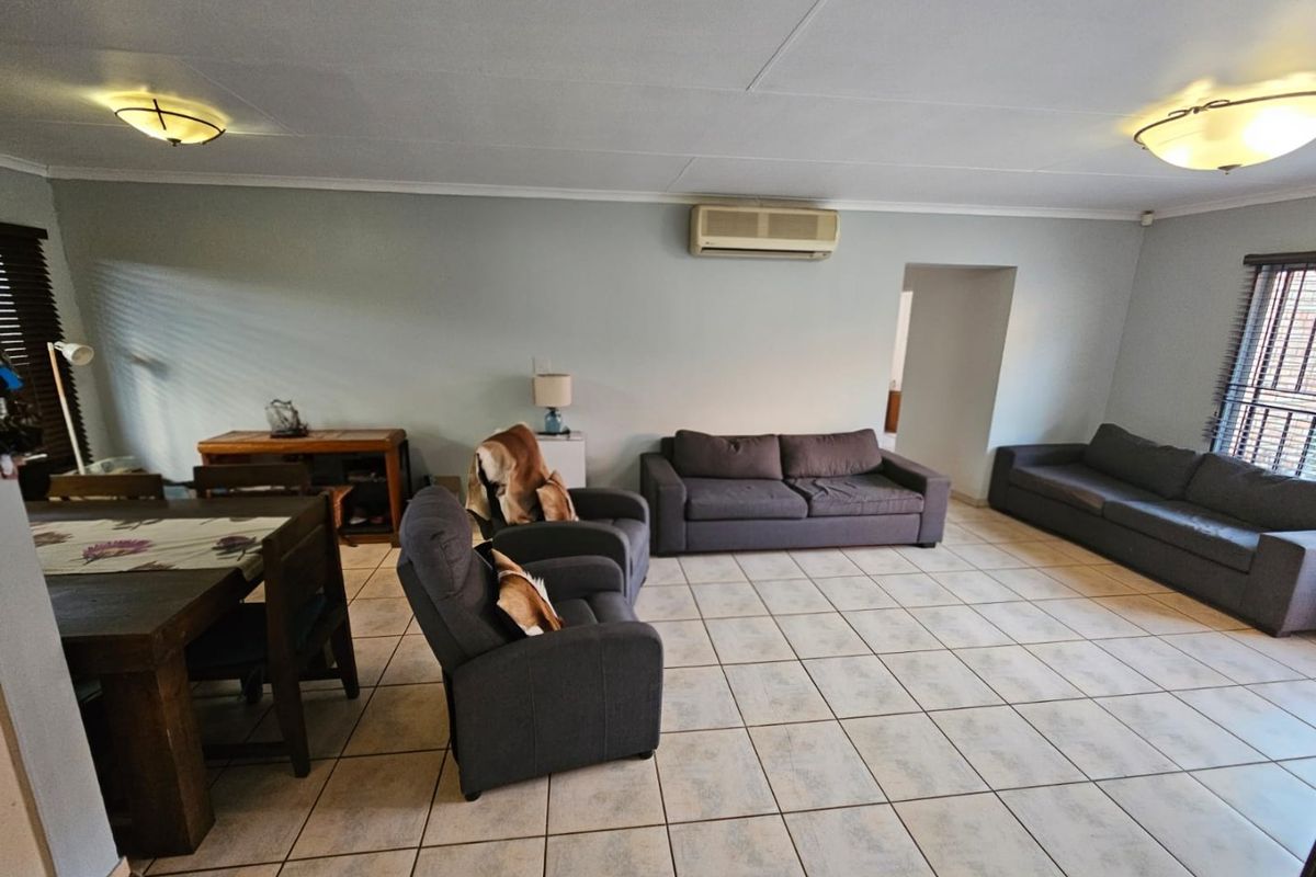 Spacious living area featuring tiled flooring, a wall-mounted air conditioning unit, and neutral wall finishes, offering a functional and open layout.