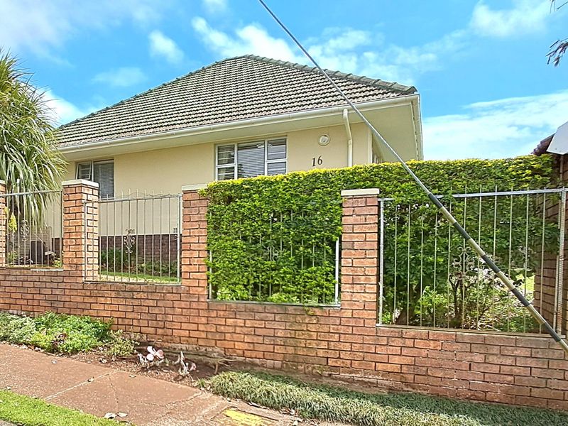 Front view of a single-story house featuring a brick boundary wall with integrated metal fencing and a tiled roof.