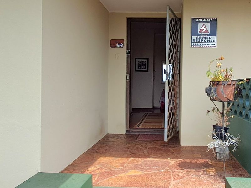 Entrance area featuring stone flooring, concrete steps, and a security gate, providing access to the home interior.