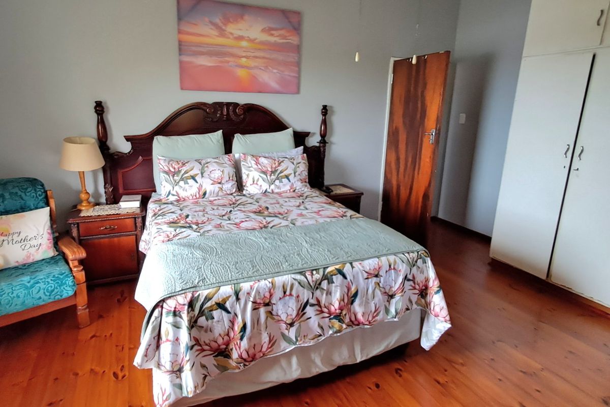 A bedroom featuring polished timber flooring, a built-in wardrobe, and a solid wood door.