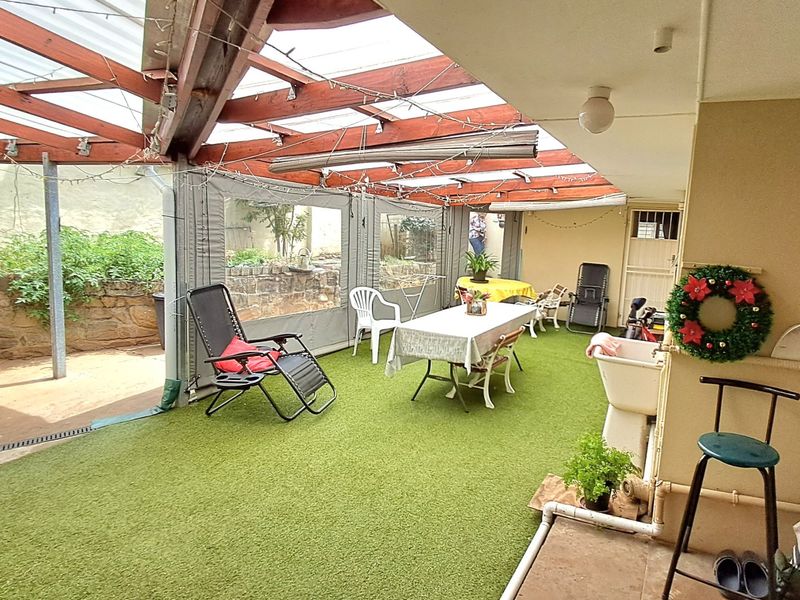 Covered outdoor patio area featuring a timber pergola with polycarbonate roofing, artificial turf flooring, and a convenient built-in utility sink.