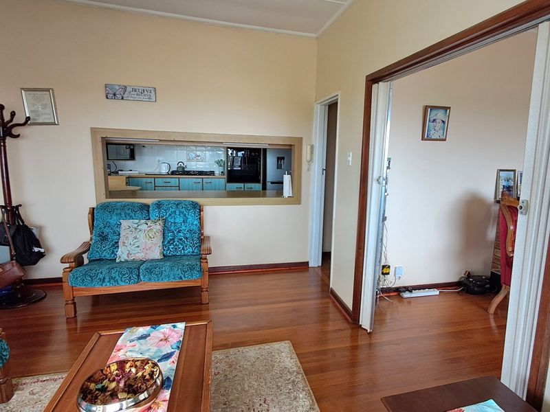 Living room featuring hardwood flooring and a serving hatch connecting to the kitchen area.