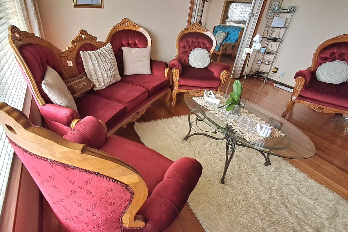 A traditional living room featuring hardwood flooring and large windows with venetian blinds, offering a classic and comfortable space.