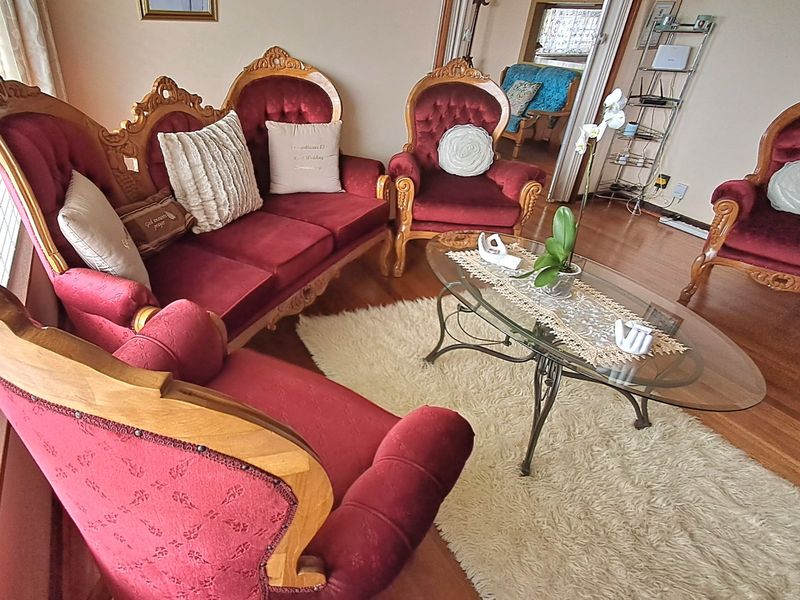 A traditional living room featuring hardwood flooring and large windows with venetian blinds, offering a classic and comfortable space.