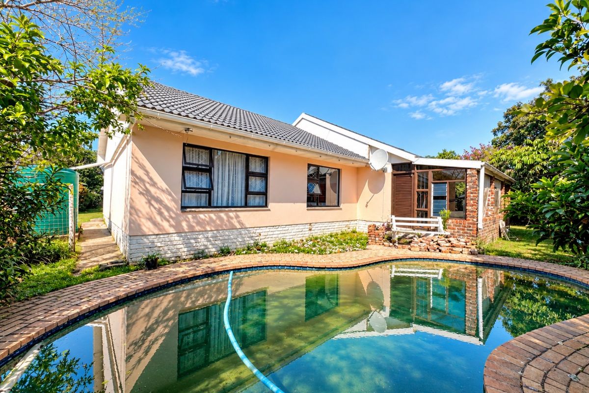 Rear view of the house featuring a swimming pool with brick paving, a tiled roof, and a garden area with a water tank.