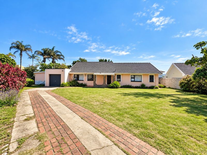 A well-maintained single-story house featuring a tiled roof, a spacious front lawn, and a brick-paved driveway leading to an attached garage.