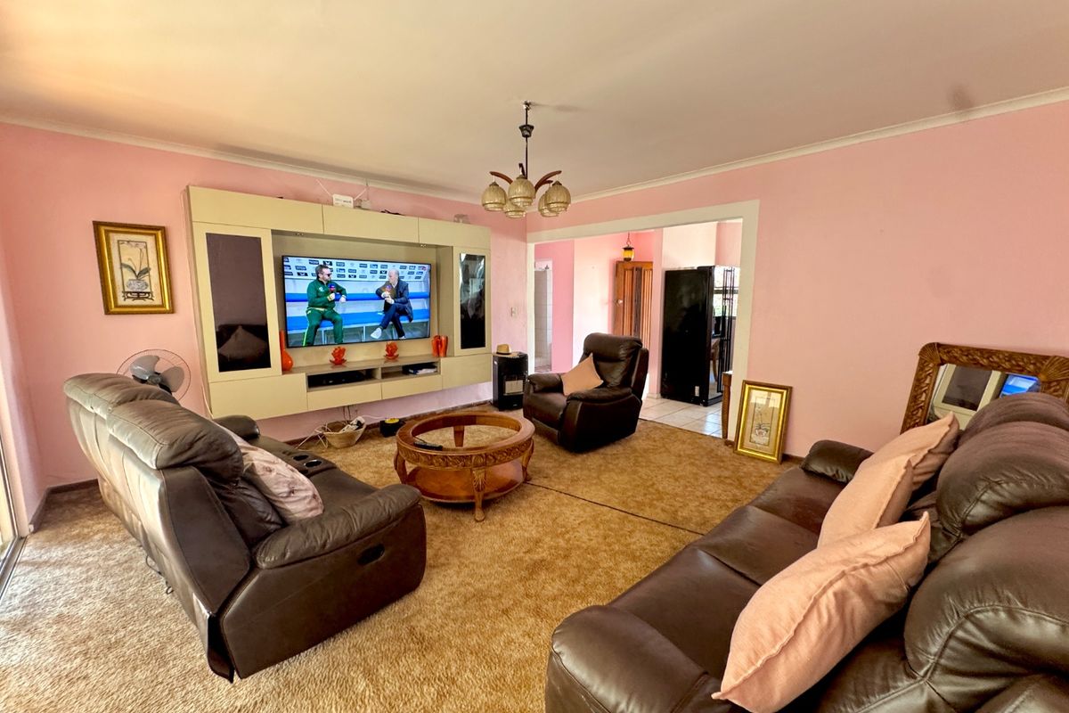 A spacious living room featuring a built-in media unit, carpeted flooring, and a central light fixture, offering a functional layout for relaxation.