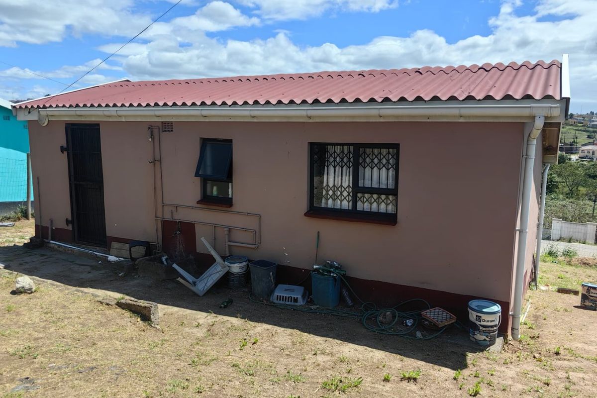 Rear exterior view of the house featuring a corrugated metal roof, security gates, and security bars on the windows.