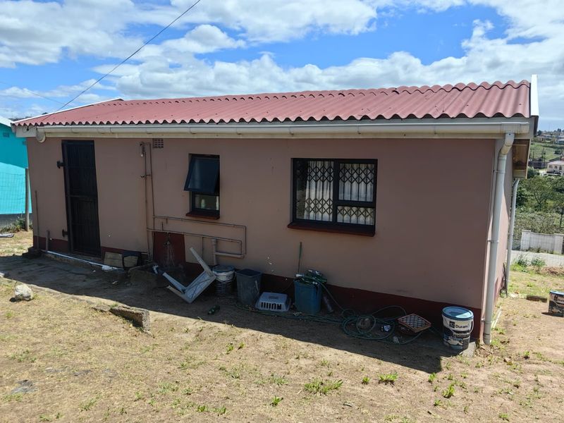 Rear exterior view of the house featuring a corrugated metal roof, security gates, and security bars on the windows.