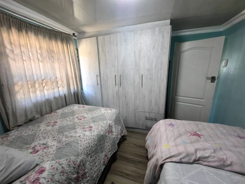 A bedroom featuring built-in cupboards, laminate flooring, and decorative cornicing, providing functional storage and a neutral foundation for interior updates.