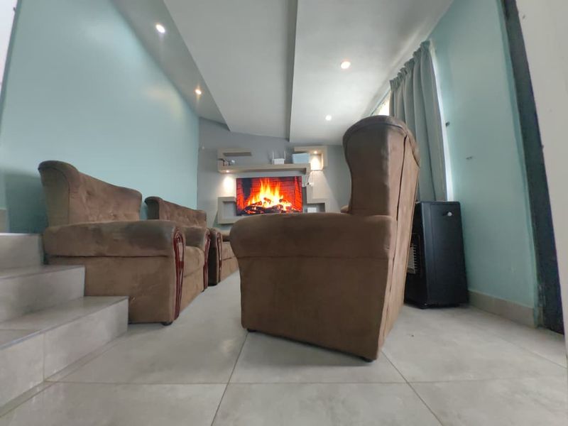 A living room featuring tiled flooring, recessed ceiling lighting, and built-in wall shelving units.
