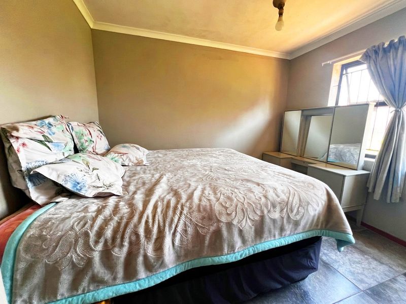 A standard bedroom featuring tiled flooring, cove cornicing, and security bars on the window.