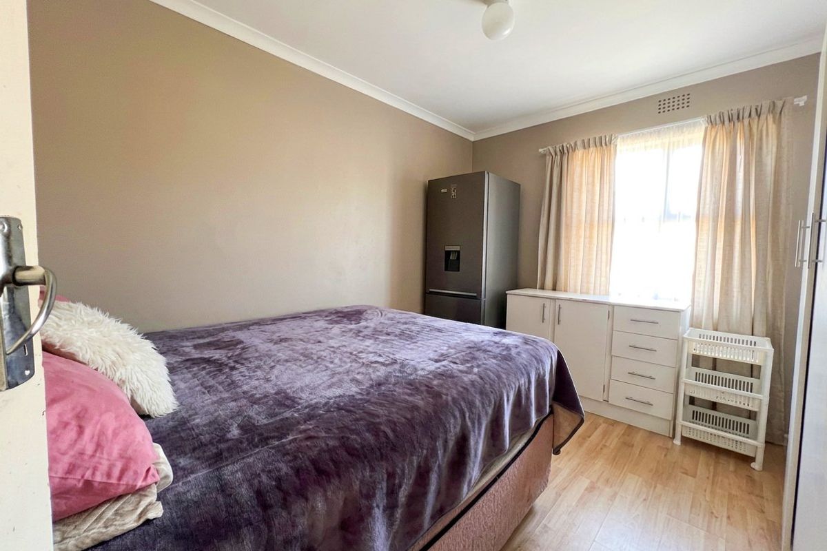 A functional bedroom featuring laminate flooring, coved ceilings, and a built-in cupboard, offering a neutral base for personalization.