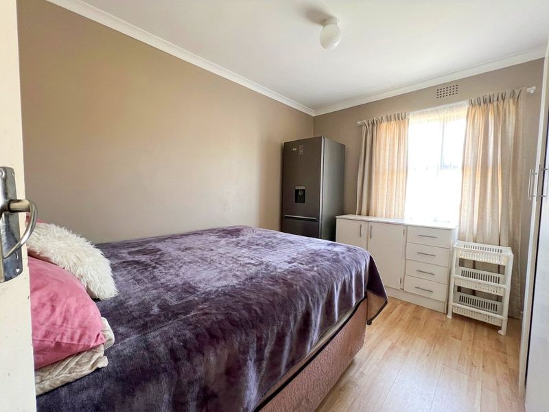 A functional bedroom featuring laminate flooring, coved ceilings, and a built-in cupboard, offering a neutral base for personalization.