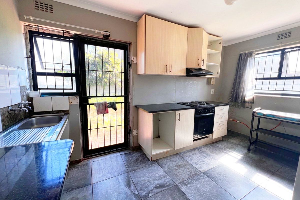 A functional kitchen featuring built-in cabinetry, a built-in oven with hob, and tiled flooring, with direct access to the rear exterior.
