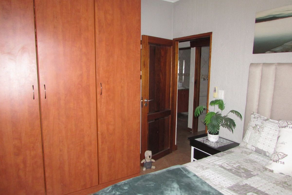 A bedroom featuring a large built-in wooden wardrobe, coving, and direct access to an adjoining bathroom.