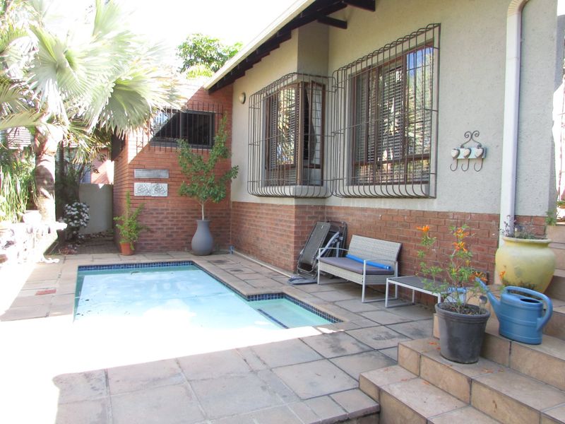 Outdoor pool area featuring a paved patio, brick wall accents, and security bars on windows, providing a functional space for outdoor relaxation.