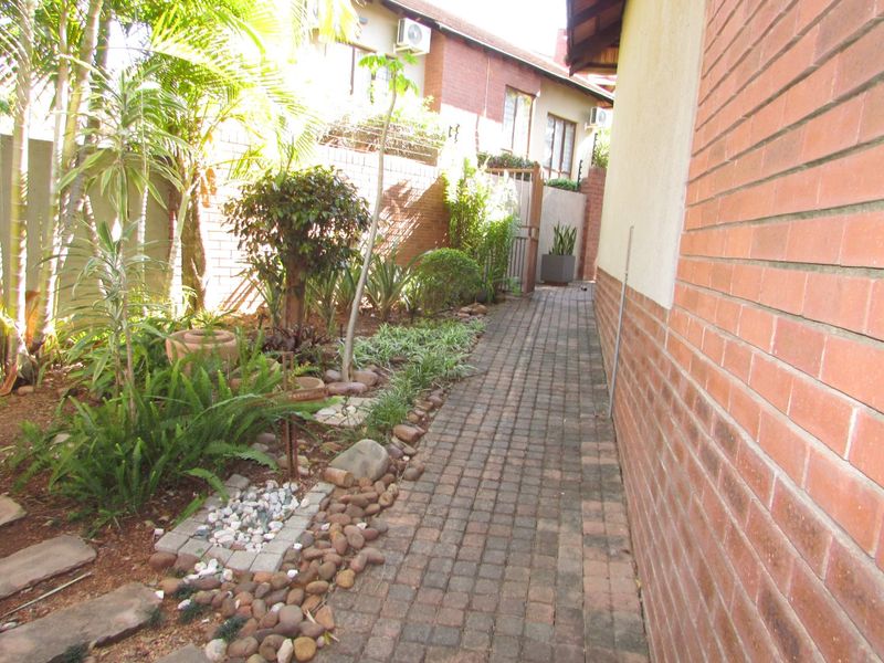 A side walkway featuring brick paving alongside a landscaped garden and brick boundary wall.