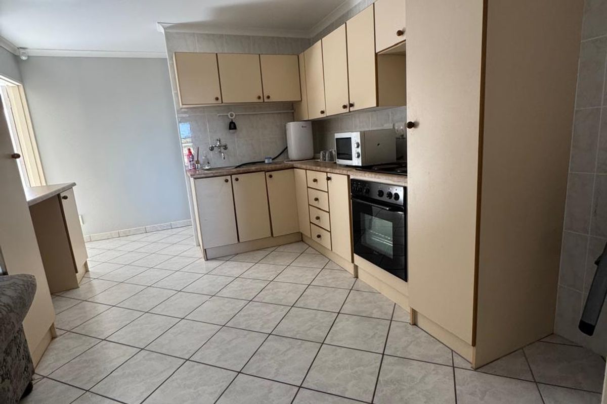 A functional kitchen featuring dated built-in cabinetry, laminate countertops, a built-in oven, and tiled flooring throughout.