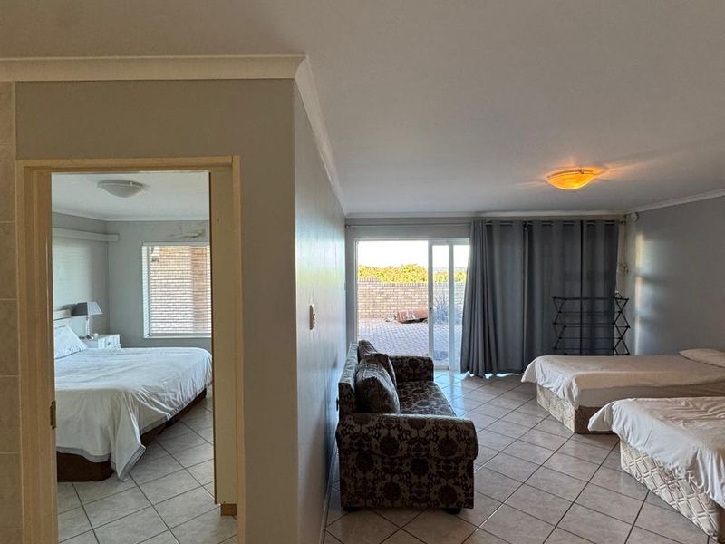 Open plan living area featuring ceramic floor tiles and a sliding glass door leading to the exterior, with an adjoining bedroom space.