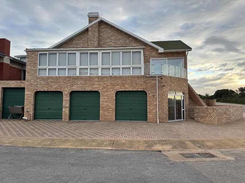 Front elevation of a multi-level brick house featuring a triple garage, paved driveway, and an upper-level balcony with glass balustrades.