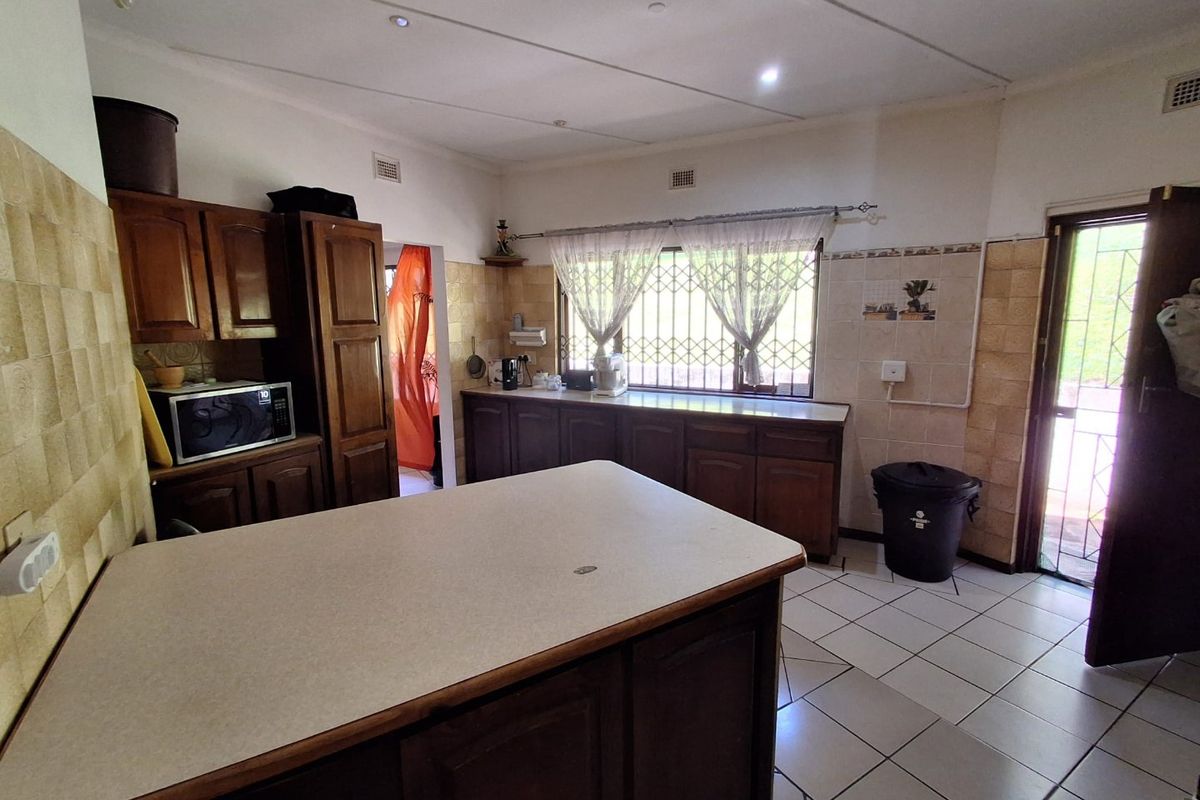 A functional kitchen featuring traditional wooden cabinetry, laminate countertops, tiled backsplash, and ceramic flooring with direct access to the exterior.
