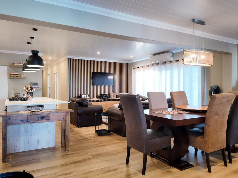 Spacious open-plan living and dining area featuring a modern kitchen island, timber slat feature wall, and contemporary lighting throughout.