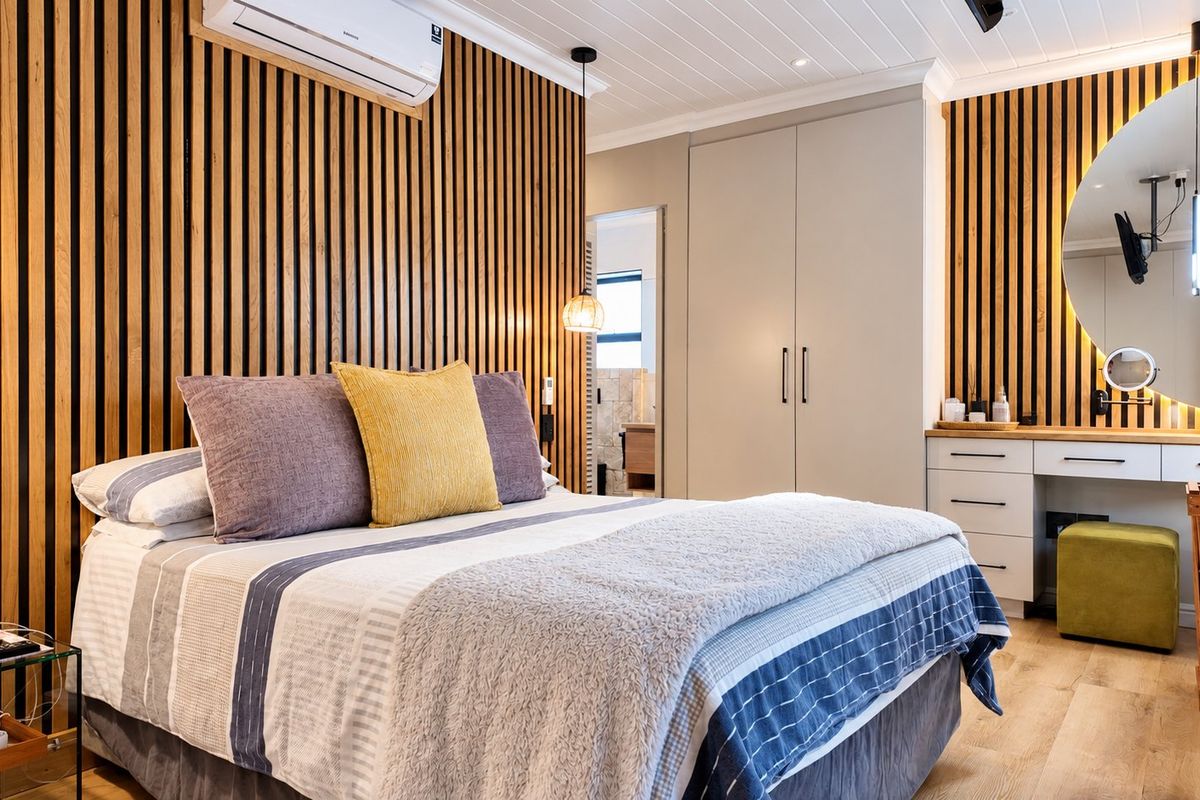 Modern bedroom featuring stylish timber slat wall paneling, built-in wardrobe, integrated vanity unit, and split-system air conditioning with high-quality finishes.