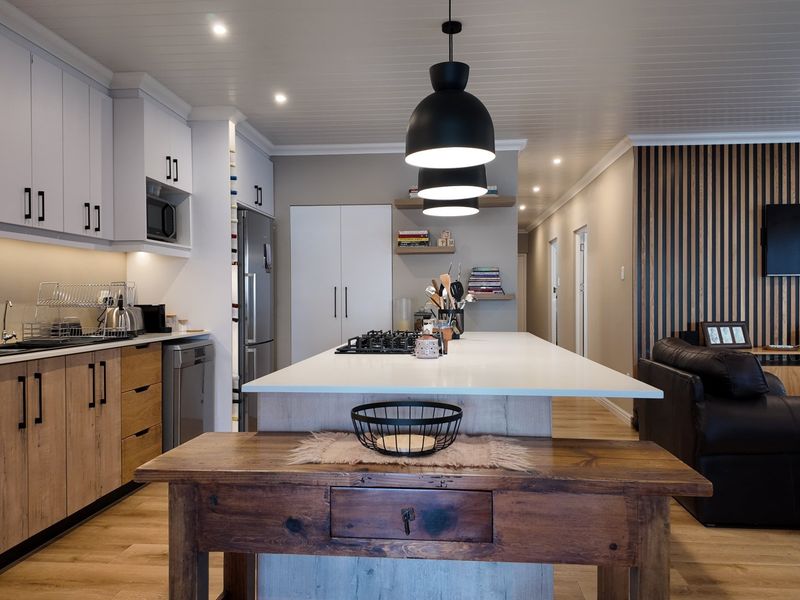 Modern open-plan kitchen featuring a central island with gas cooktop, sleek cabinetry, and a stylish timber slat feature wall in the adjacent living area.