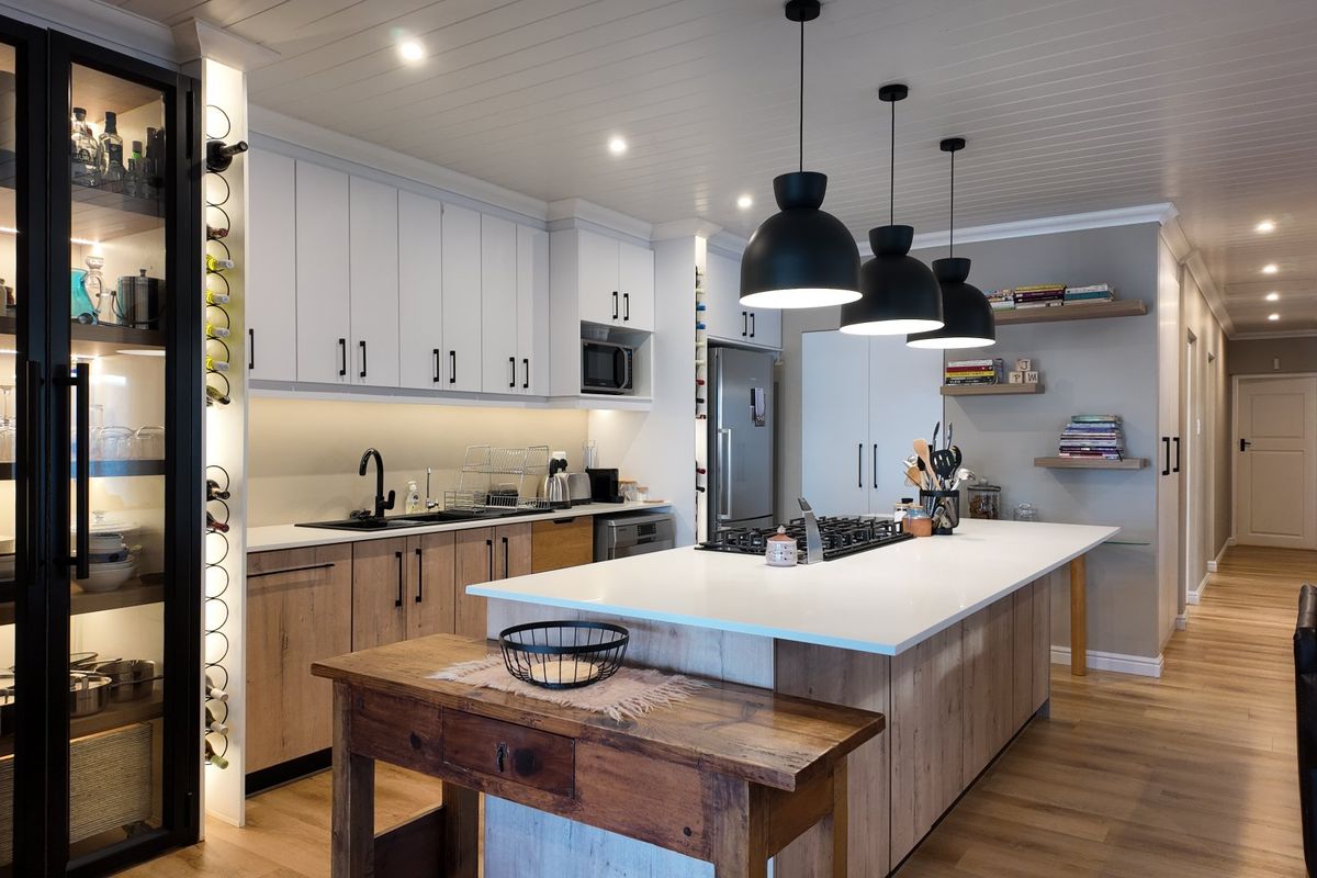 Modern, well-appointed kitchen featuring a large island with stone countertops, gas cooktop, integrated appliances, and stylish pendant lighting with ample storage cabinetry.