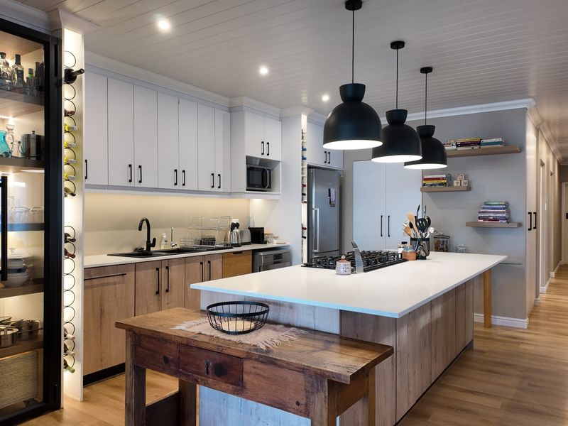 Modern, well-appointed kitchen featuring a large island with stone countertops, gas cooktop, integrated appliances, and stylish pendant lighting with ample storage cabinetry.