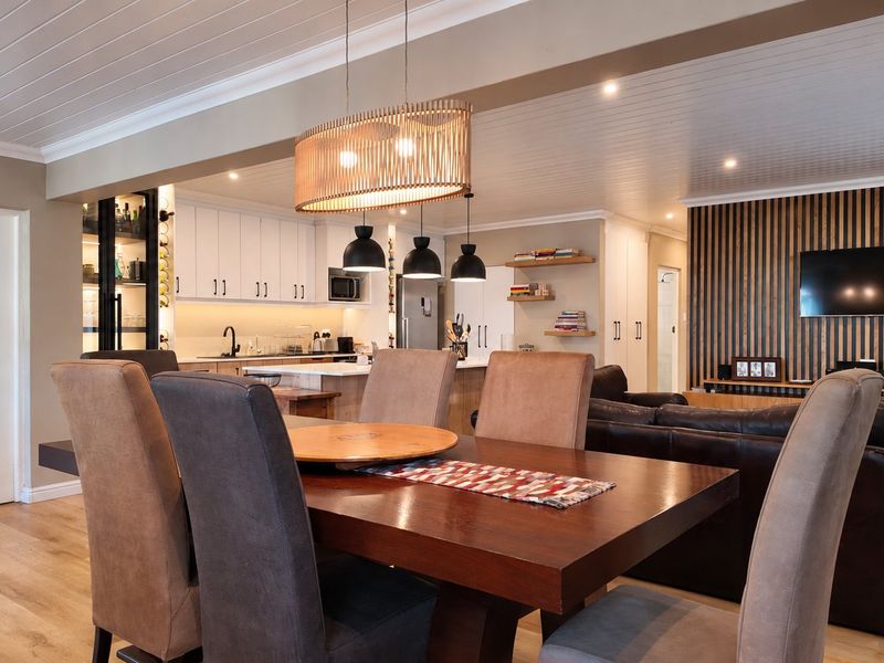 A modern open-plan living and dining area featuring a contemporary kitchen with island, timber slat wall detailing, and high-quality finishes throughout.