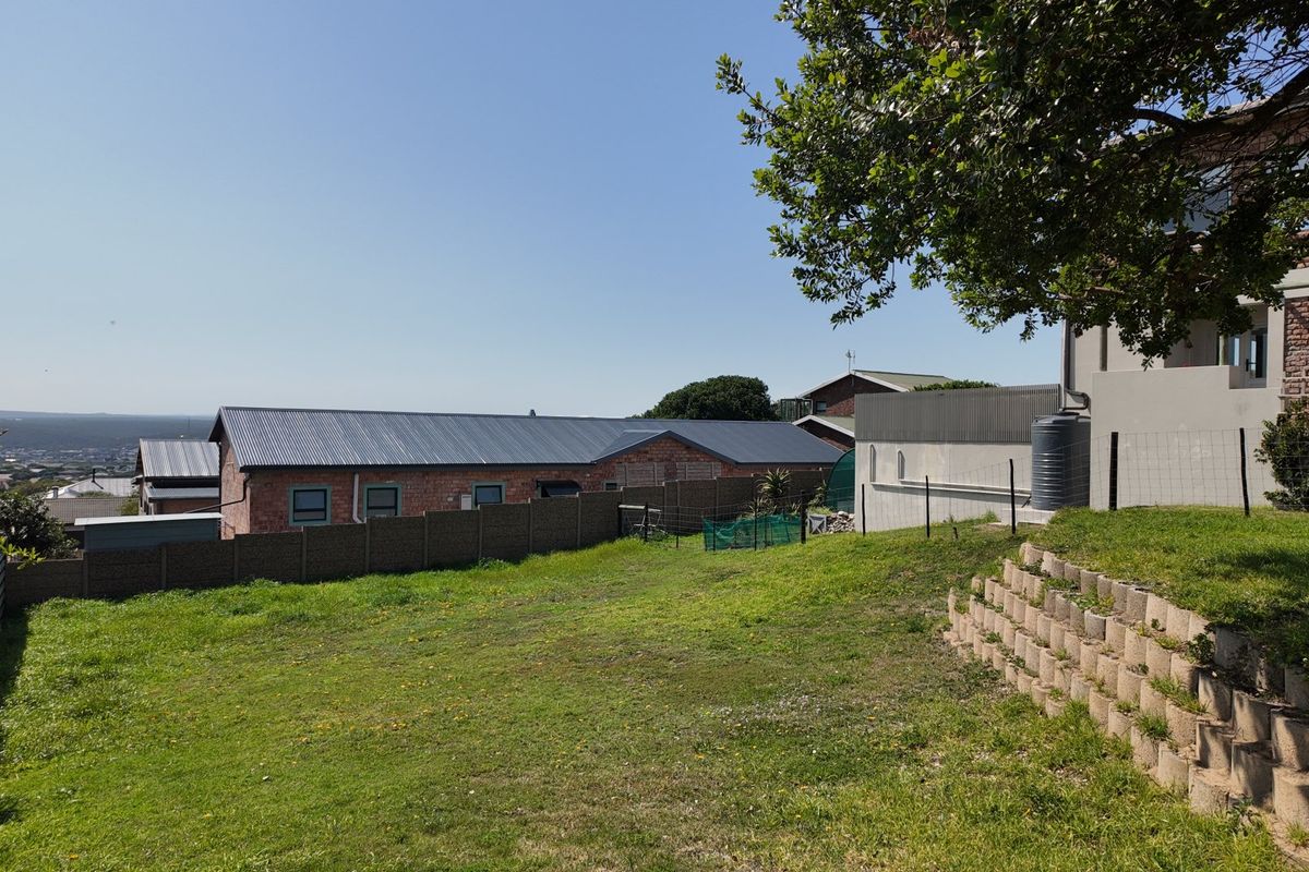 A view of the rear garden area featuring a terraced retaining wall, lawn, and boundary fencing with a water tank visible.