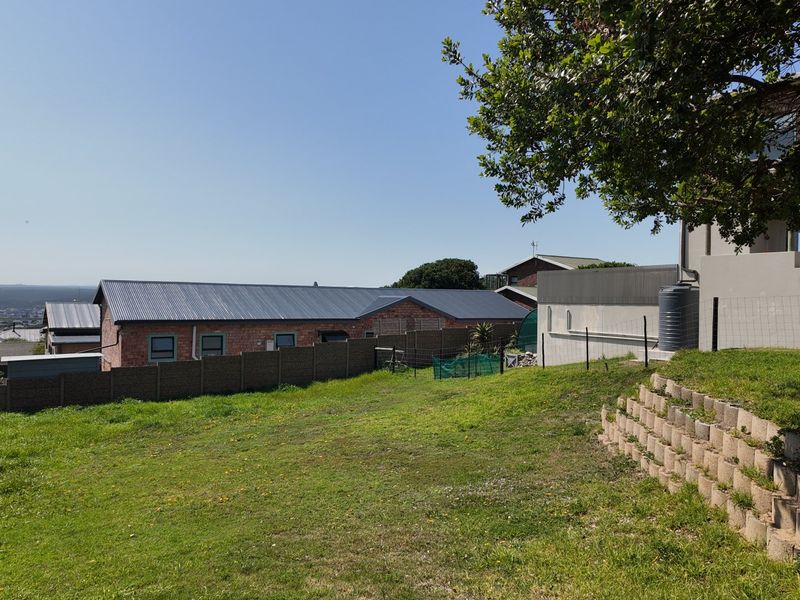 A view of the rear garden area featuring a terraced retaining wall, lawn, and boundary fencing with a water tank visible.