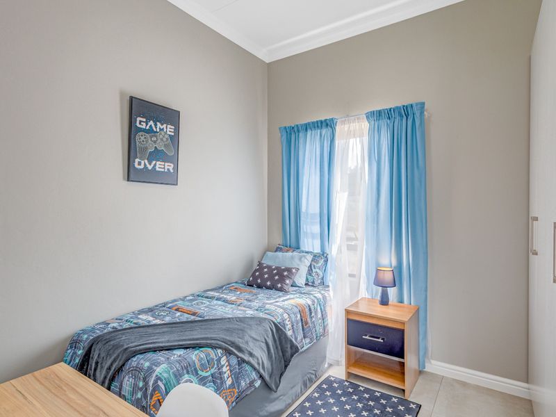 A well-maintained bedroom featuring neutral wall tones, tiled flooring, and a built-in wardrobe with modern hardware.