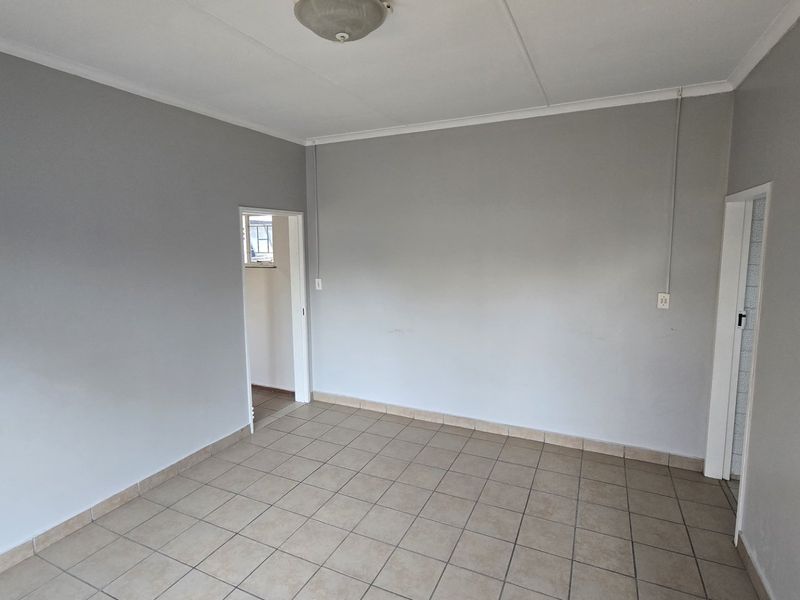An empty living area featuring neutral grey walls and tiled flooring, providing a blank canvas for interior design.