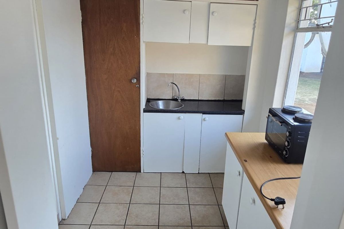 A compact kitchen featuring tiled flooring, built-in cabinetry, and a sink, offering a functional space ready for modernization and cosmetic updates.