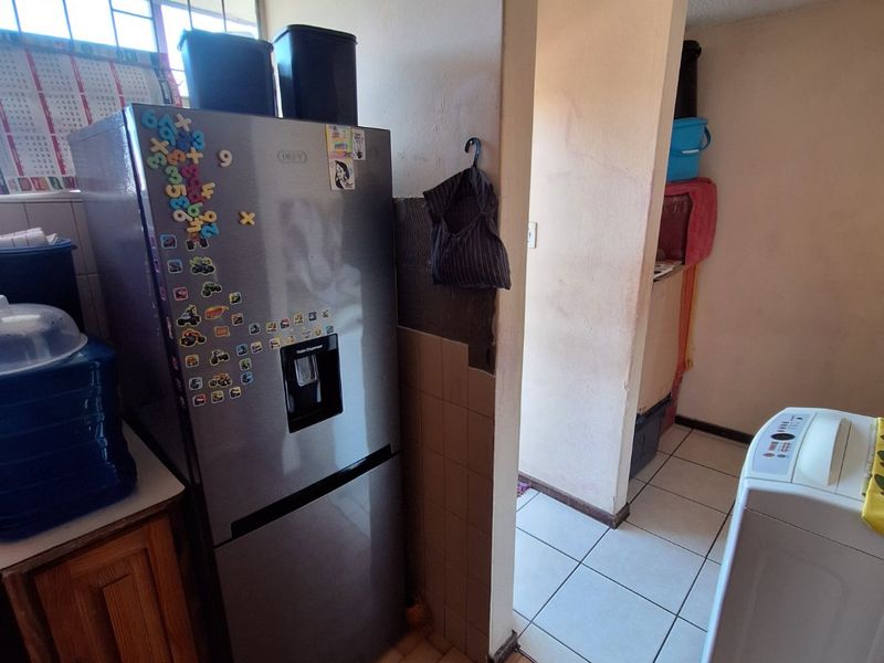 A functional laundry area featuring tiled flooring and a textured ceiling, providing a practical space for utility tasks within the apartment.