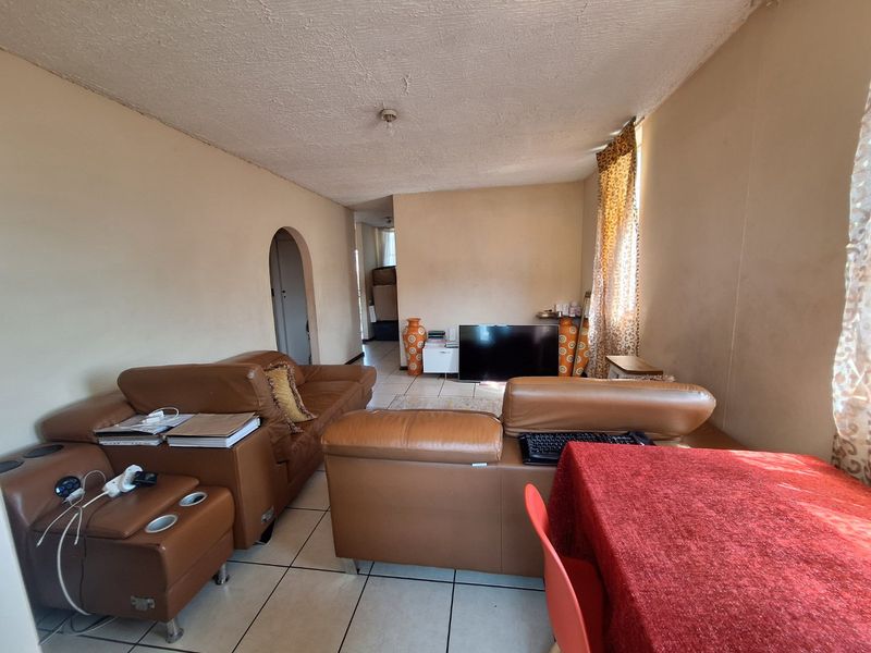 A living room area featuring tiled flooring and an arched doorway, showing signs of wear on the walls and ceiling.